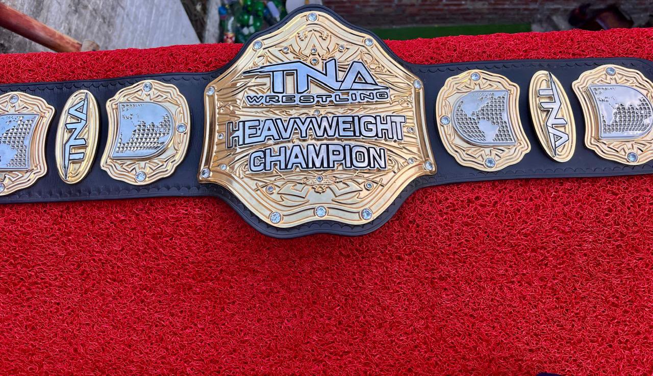 Stacked Gold heavyweight championship belt laid flat, showing the layered gold centre plate set with clear stones